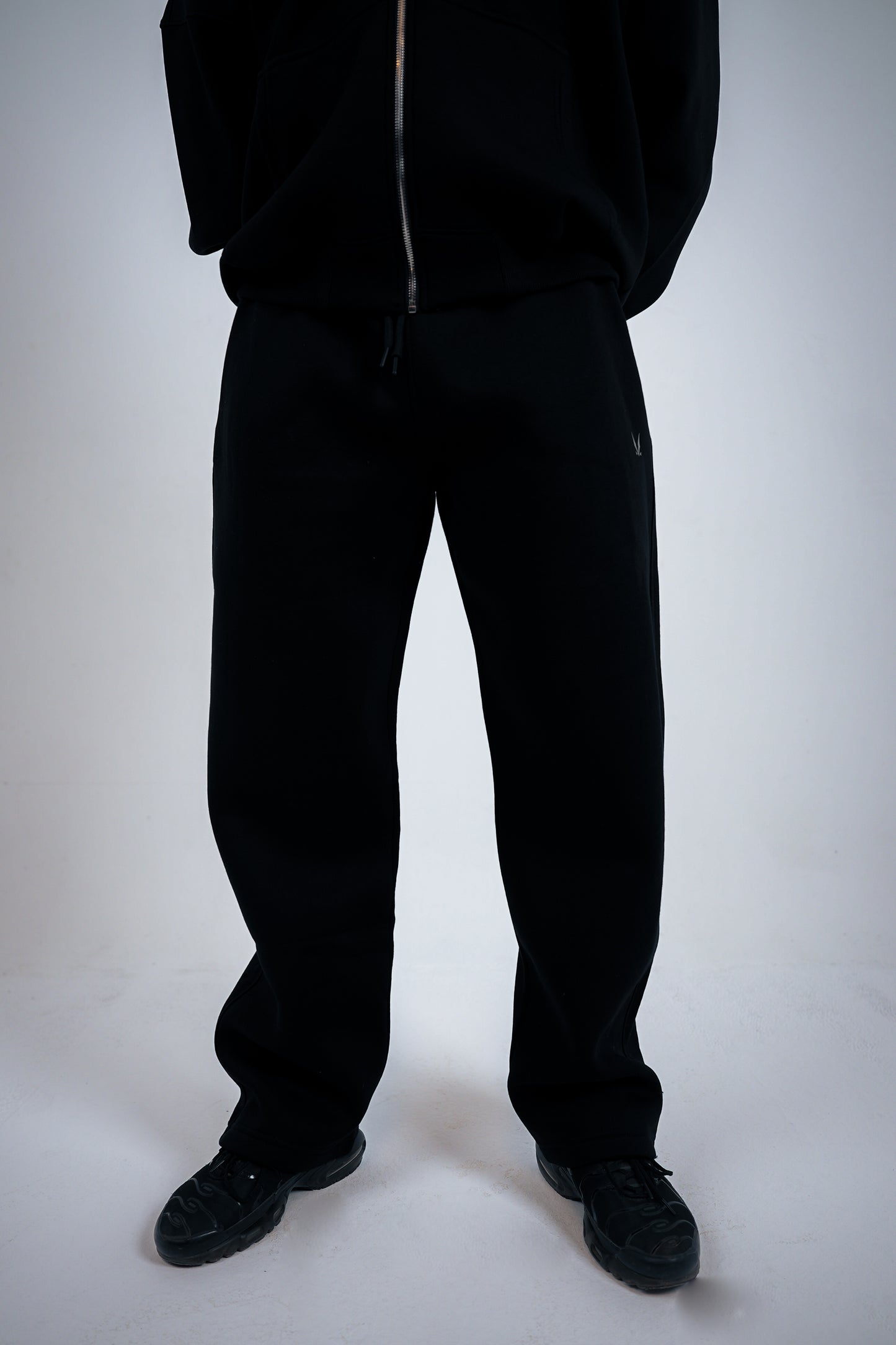 Person wearing a black RAVIX tracksuit on a white background