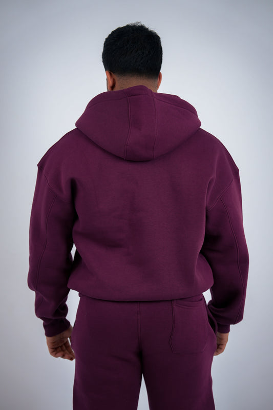 Model wearing a RAVIX maroon hoodie and pants on a light gray background
