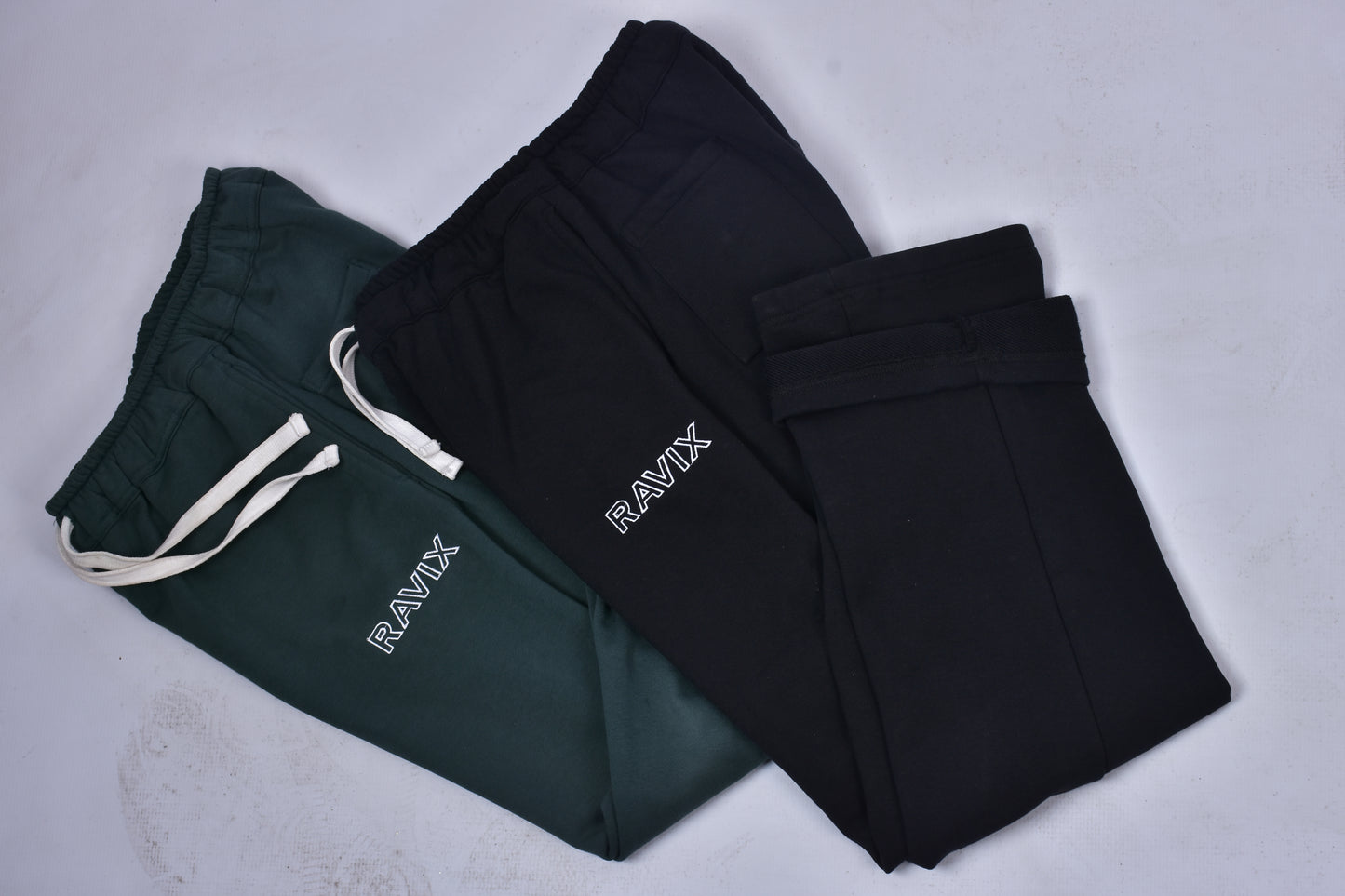 Black and green pants with 'RAVIX' branding on a light gray background