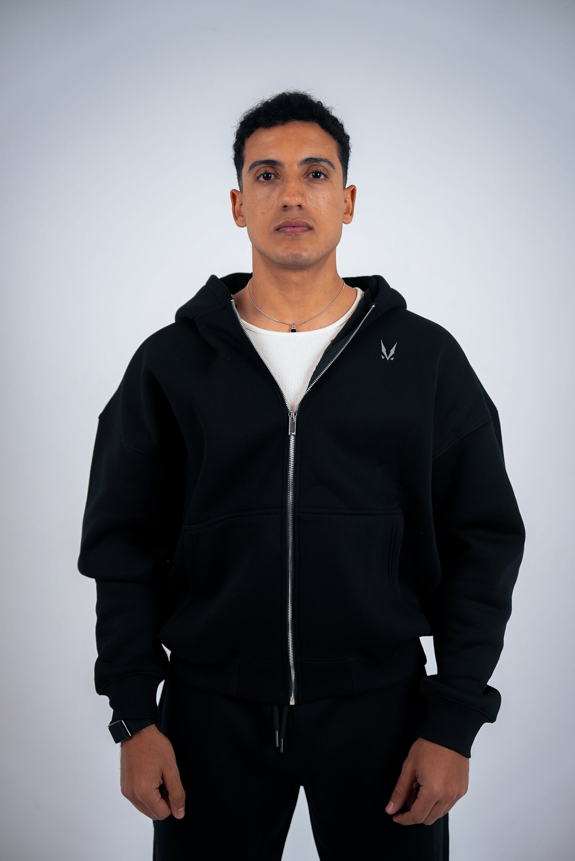 Man wearing a black hoodie with a white RAVIX logo on a light gray background