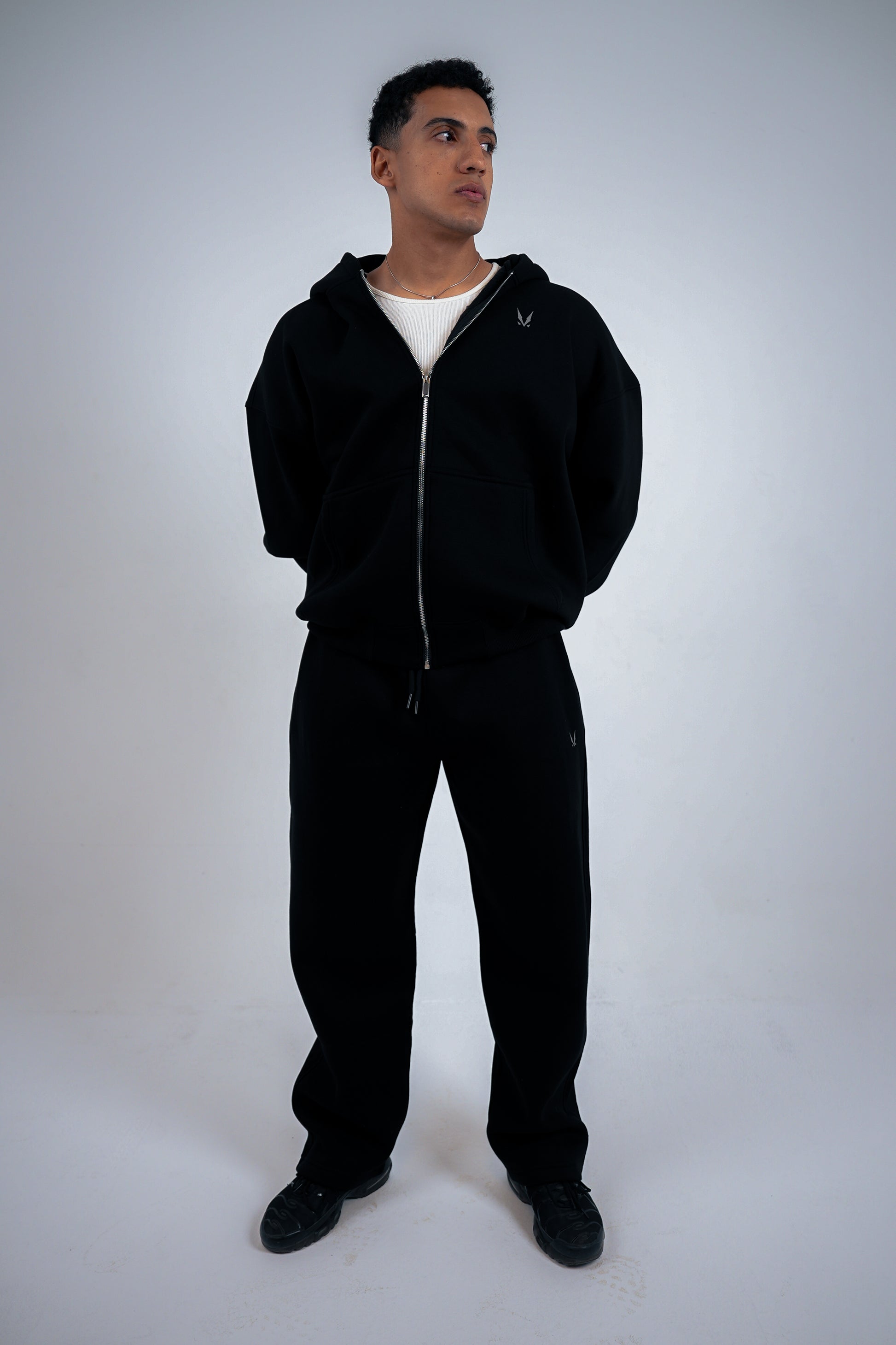 Man wearing a black RAVIX tracksuit on a white background