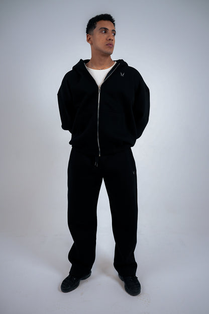 Man wearing a black RAVIX tracksuit on a white background