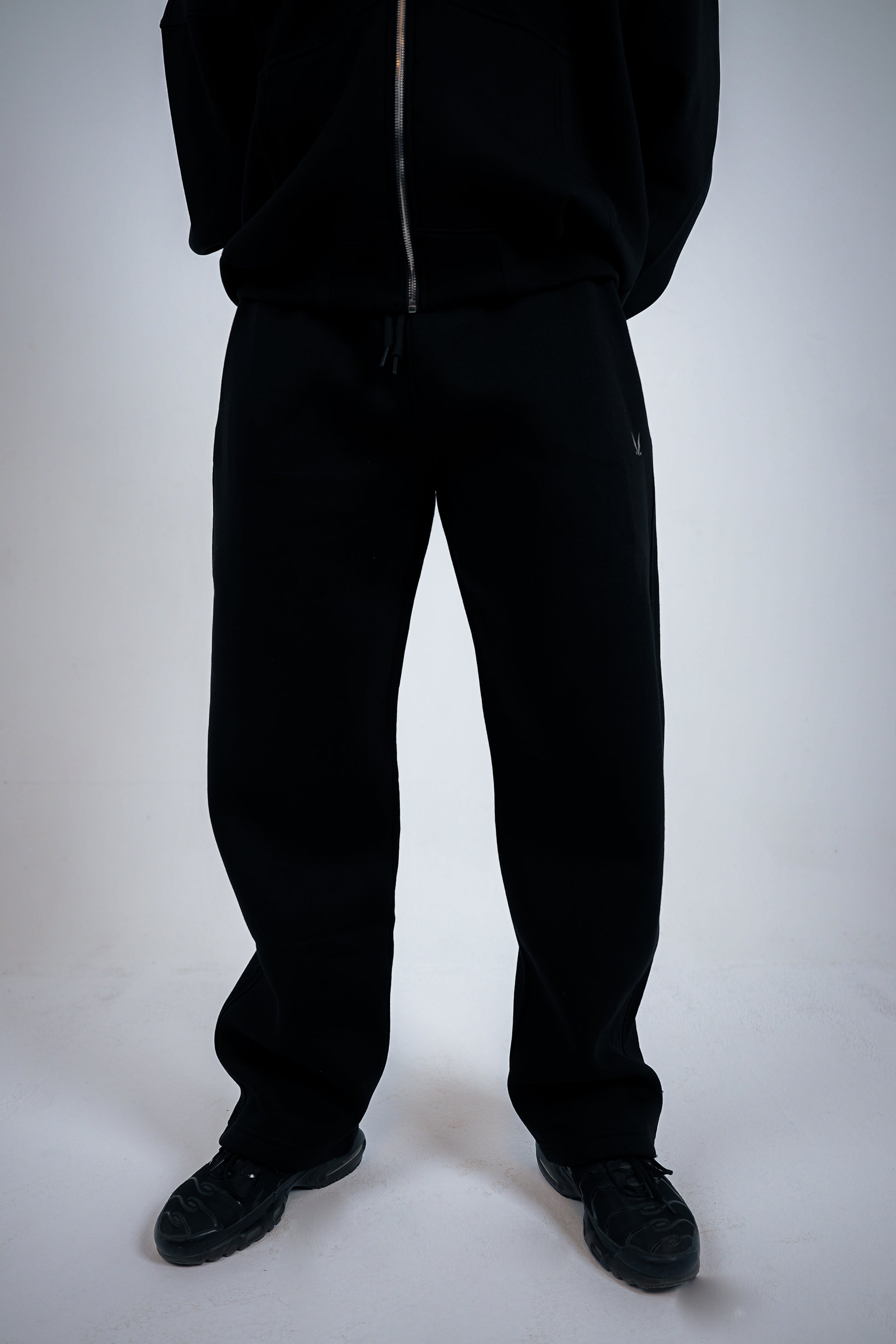 Person wearing a black RAVIX tracksuit on a white background