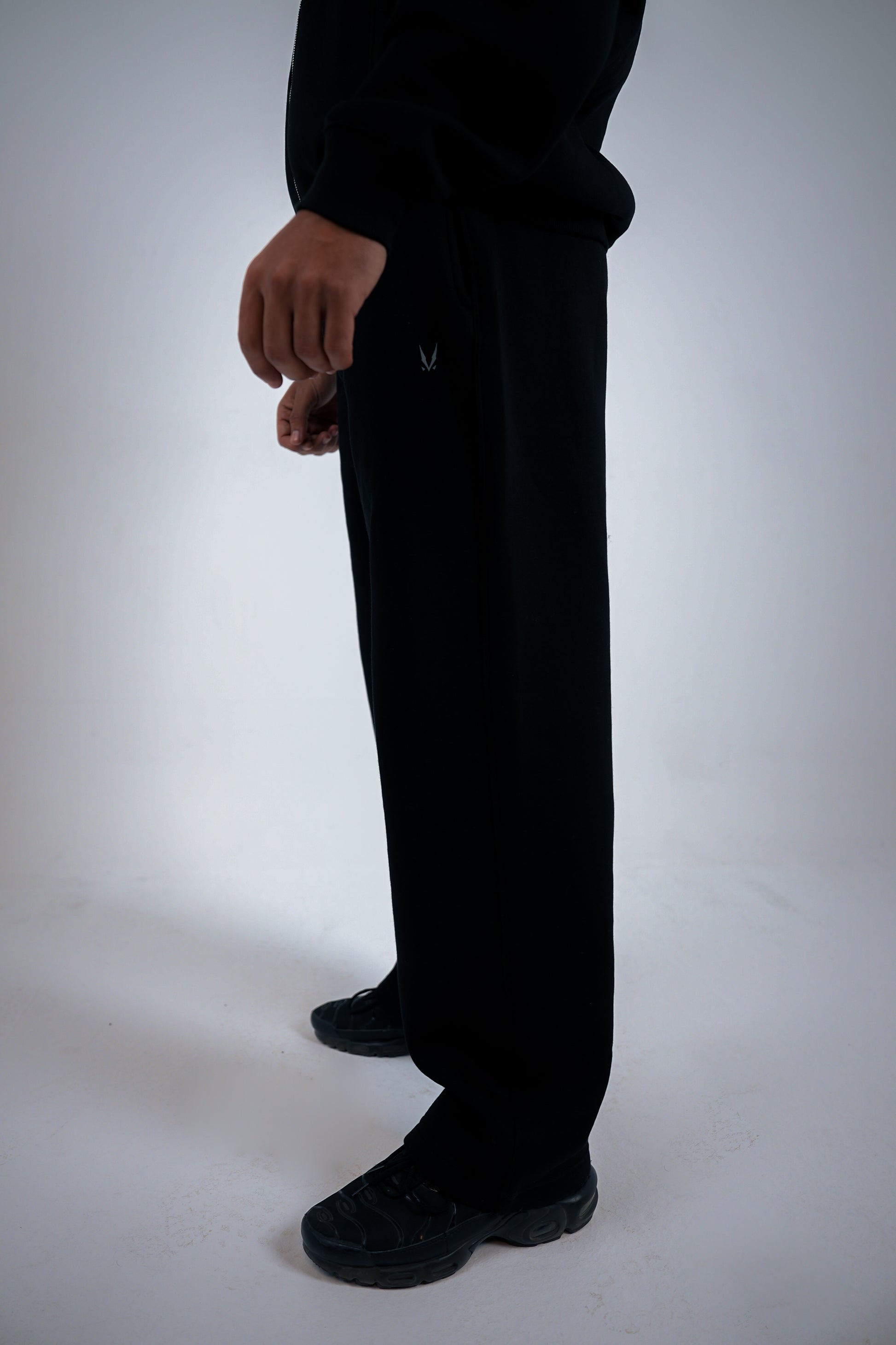 Person wearing black pants with brand RAVIX logo on a white background