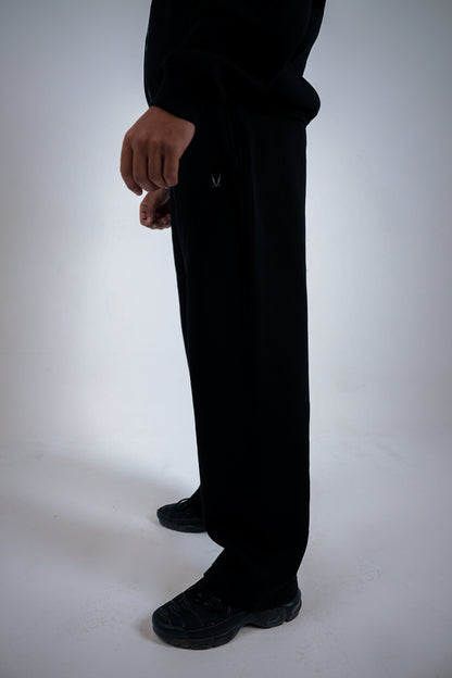 Person wearing black pants with brand RAVIX logo on a white background