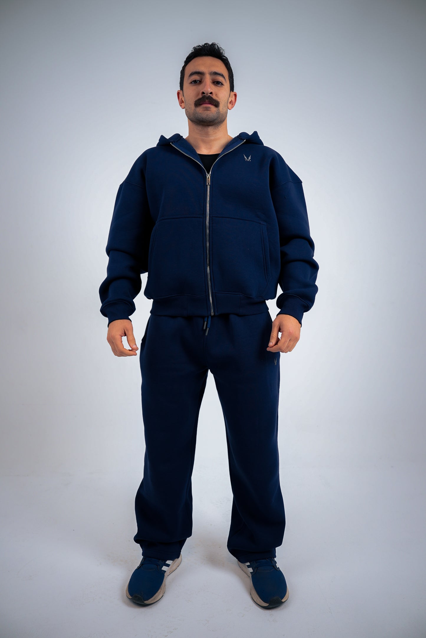 Model wearing a navy-blue RAVIX tracksuit on a light gray background