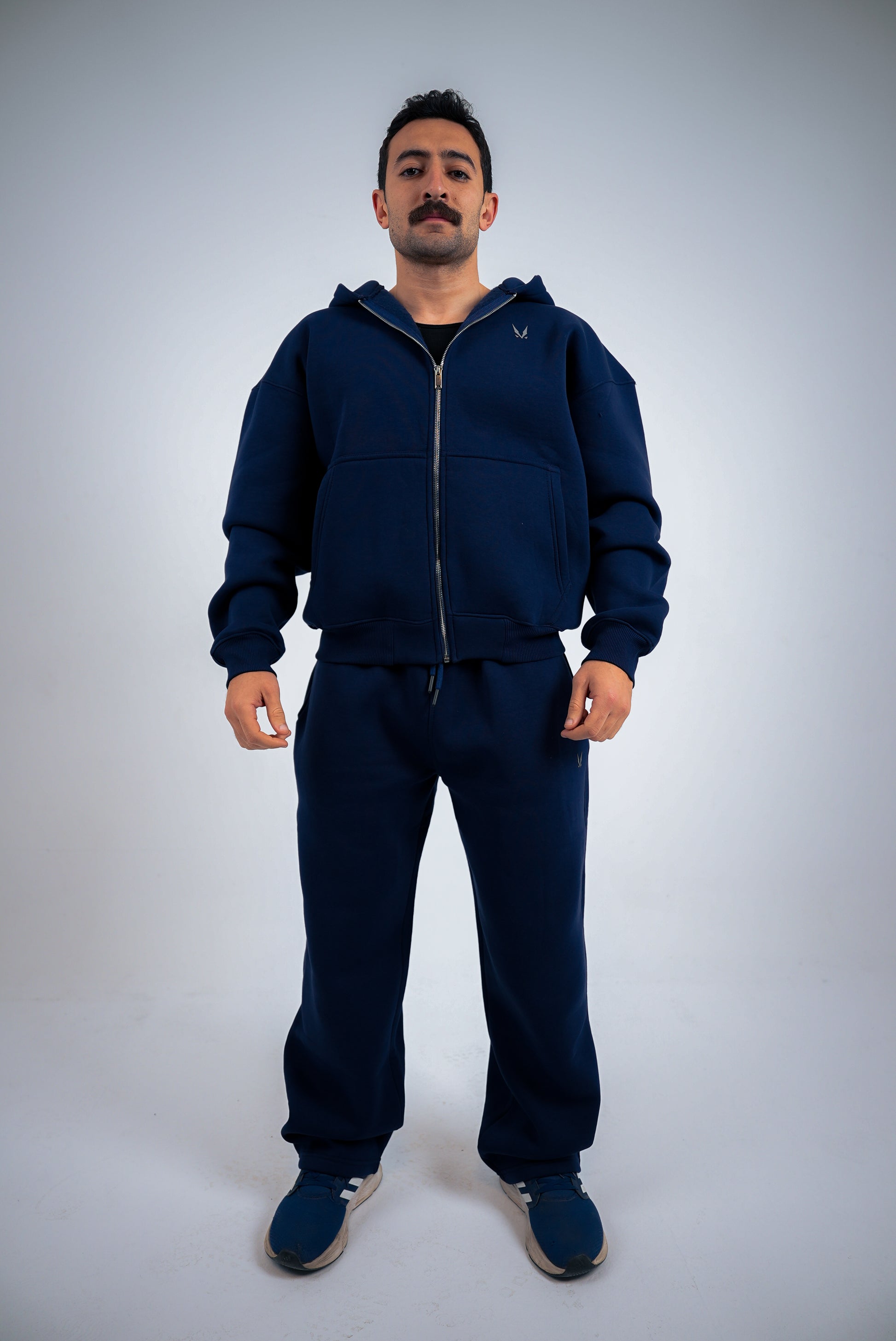 Model wearing a navy-blue RAVIX tracksuit on a light gray background