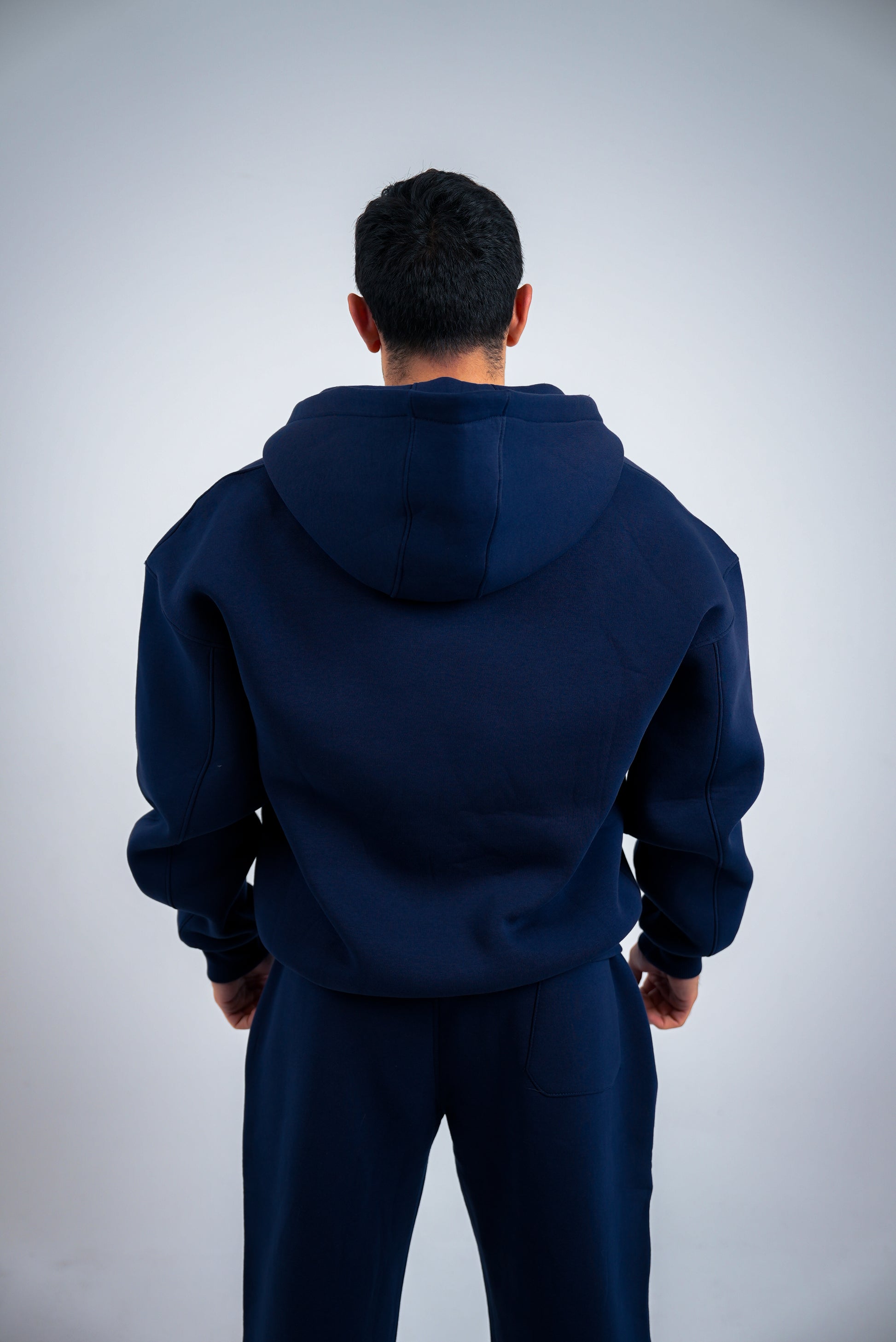 Person wearing a RAVIX navy blue hoodie and pants on a light gray background