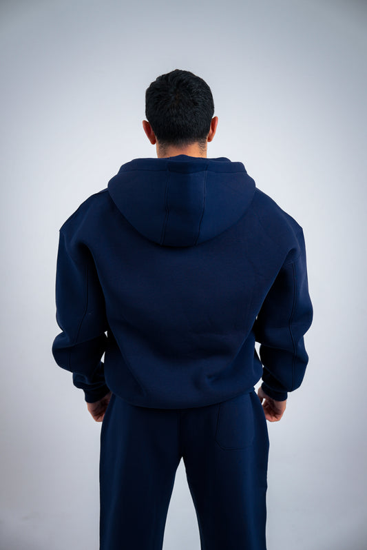 Person wearing a RAVIX navy blue hoodie and pants on a light gray background