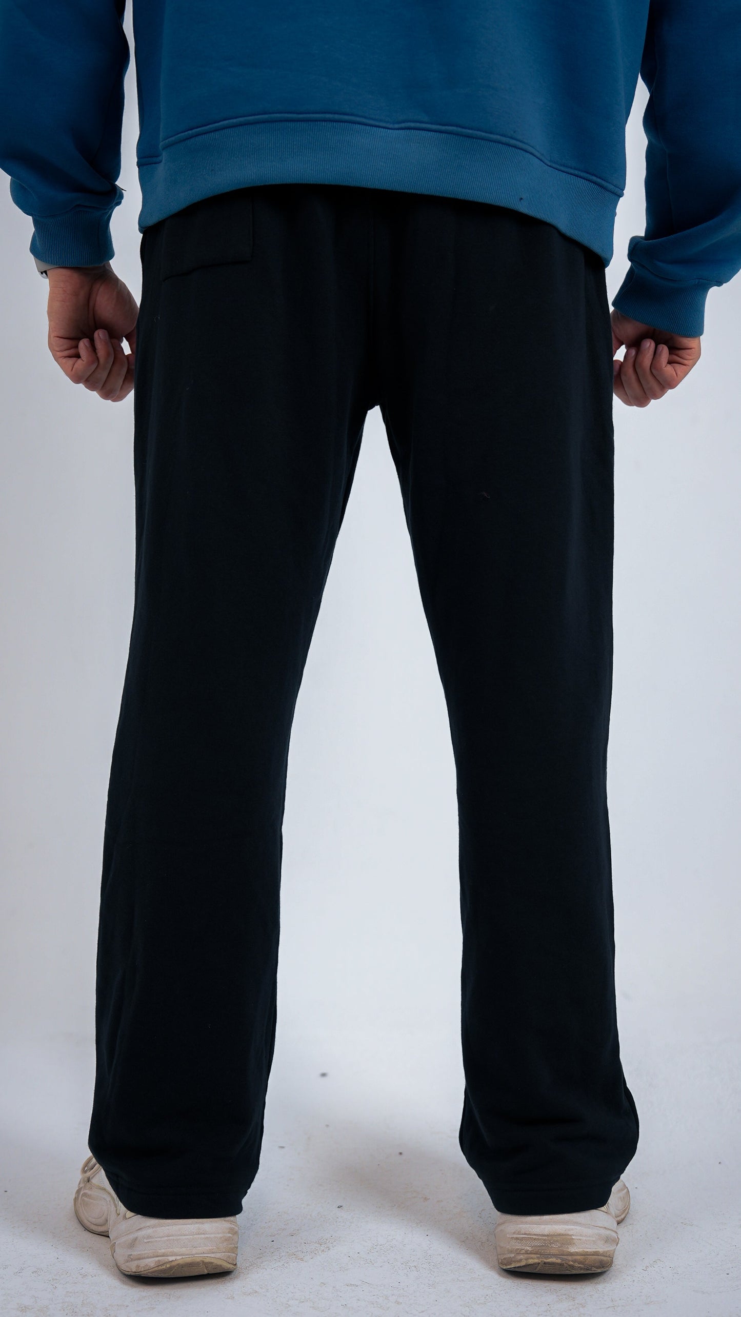 Person wearing black pants and a blue sweatshirt on a white background