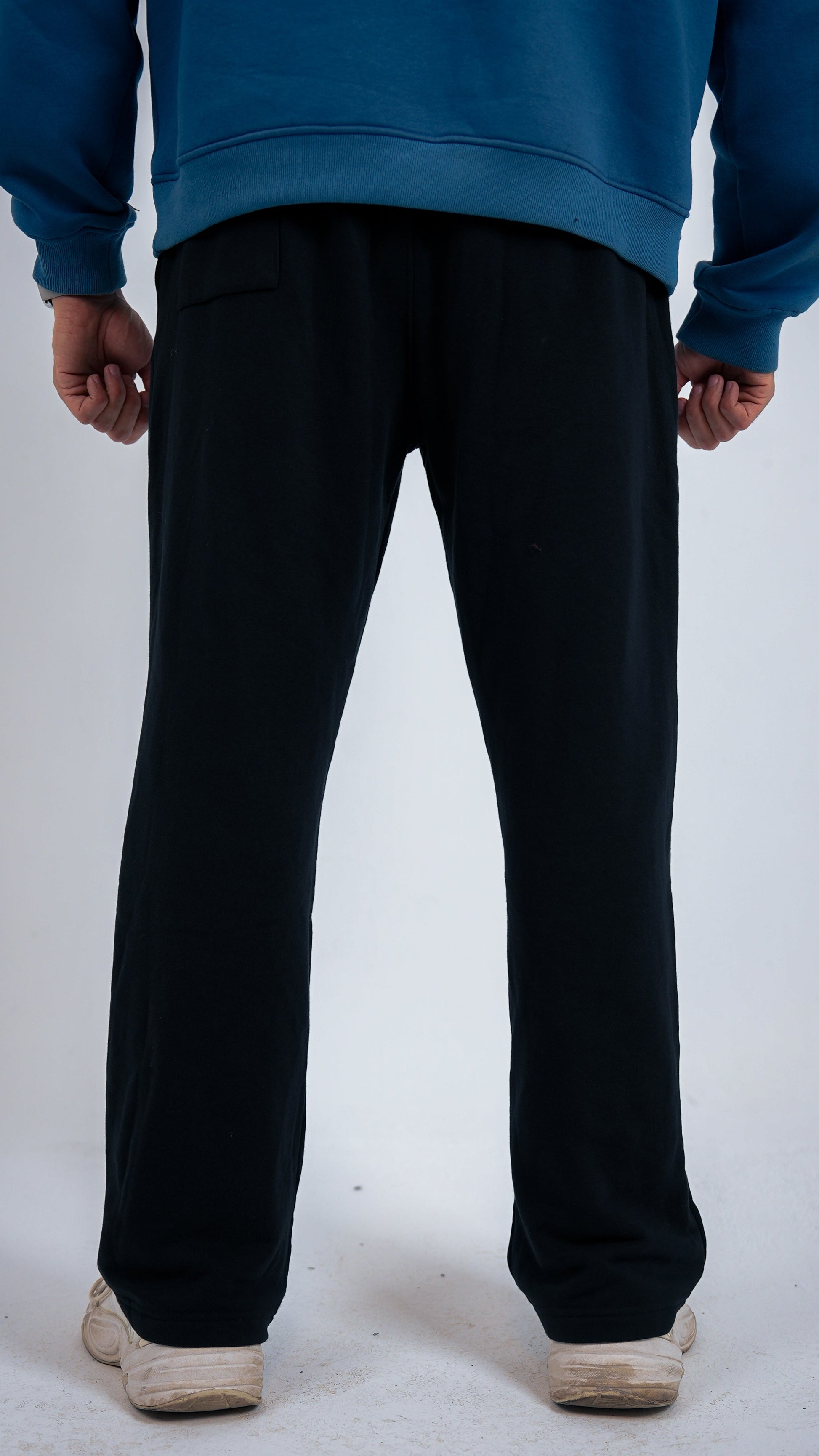 Person wearing black pants and a blue sweatshirt on a white background