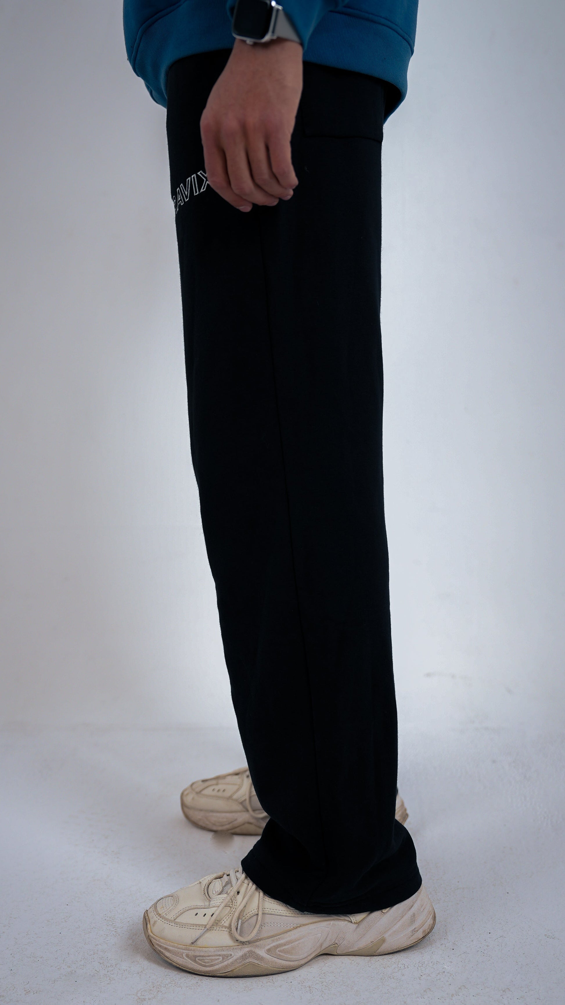 Model wearing RAVIX black pants on a white background