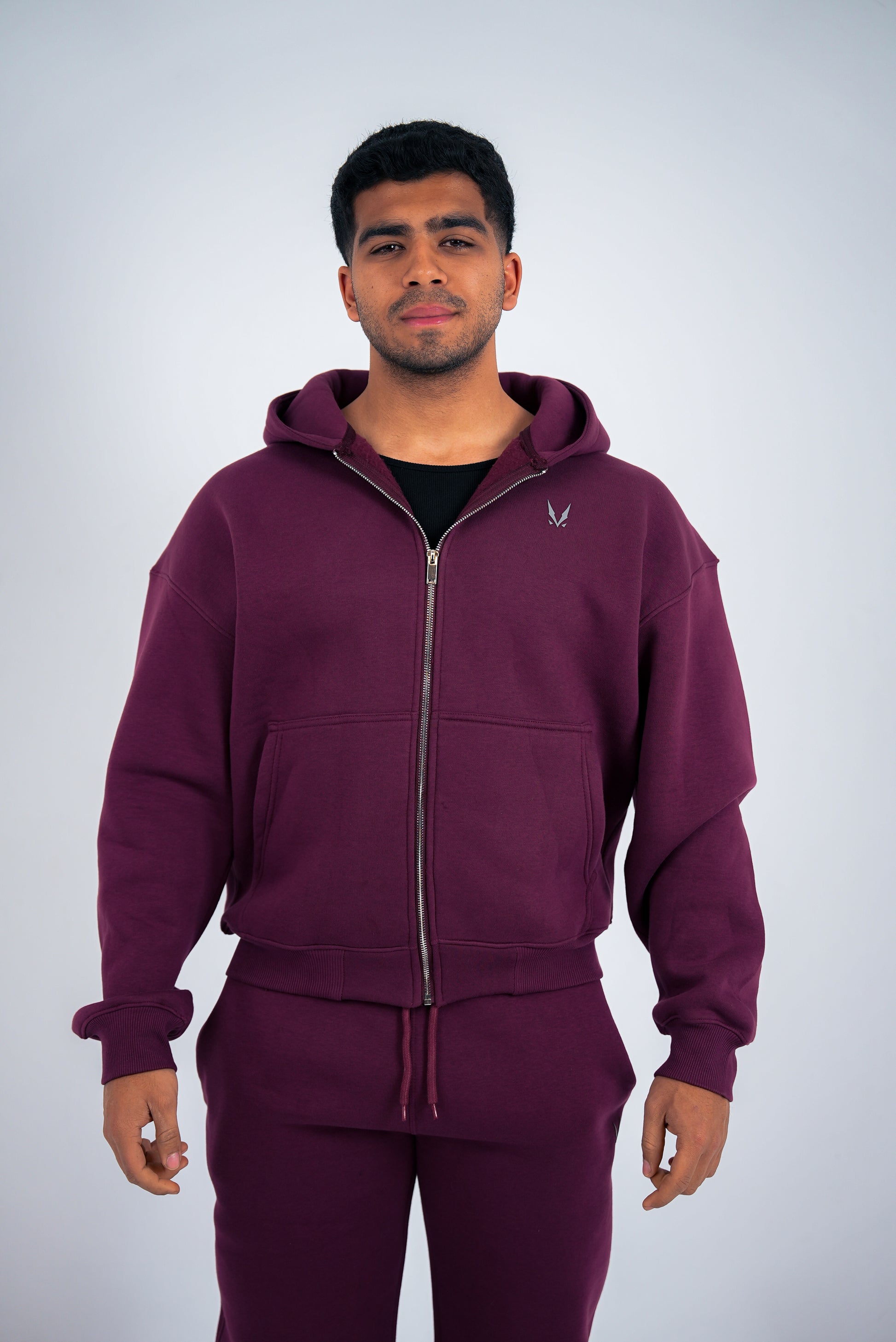 Model wearing a maroon RAVIX tracksuit with a logo on a light gray background