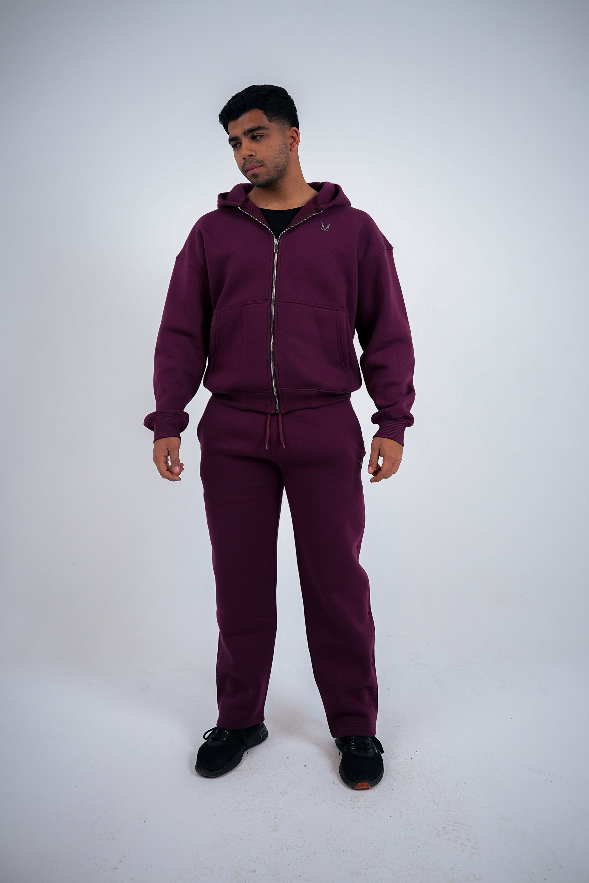 Man wearing a maroon RAVIX tracksuit on a white background