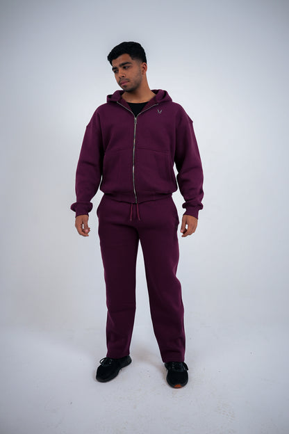 Man wearing a maroon RAVIX tracksuit on a white background