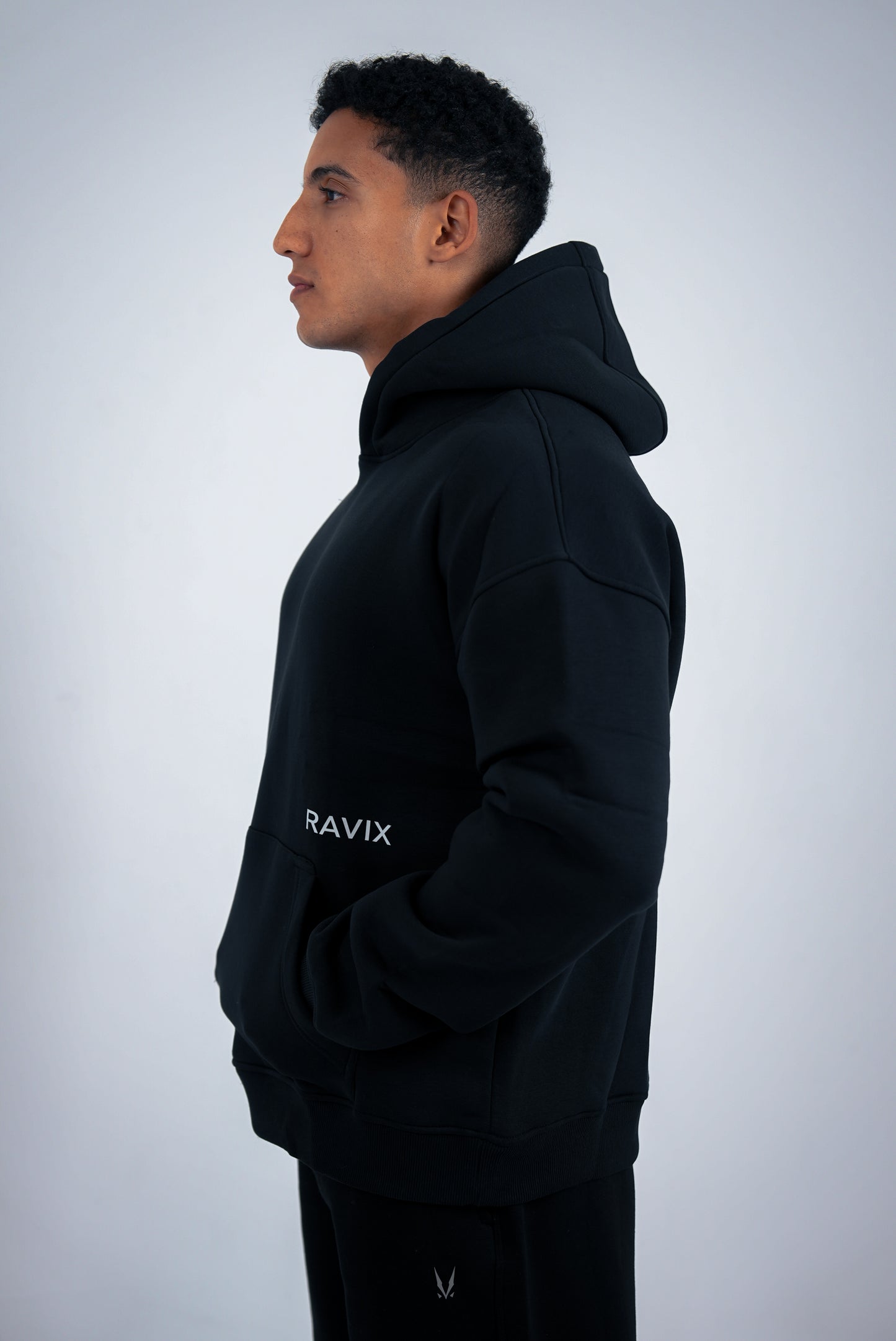 Person wearing a black hoodie with 'RAVIX' branding on a light gray background