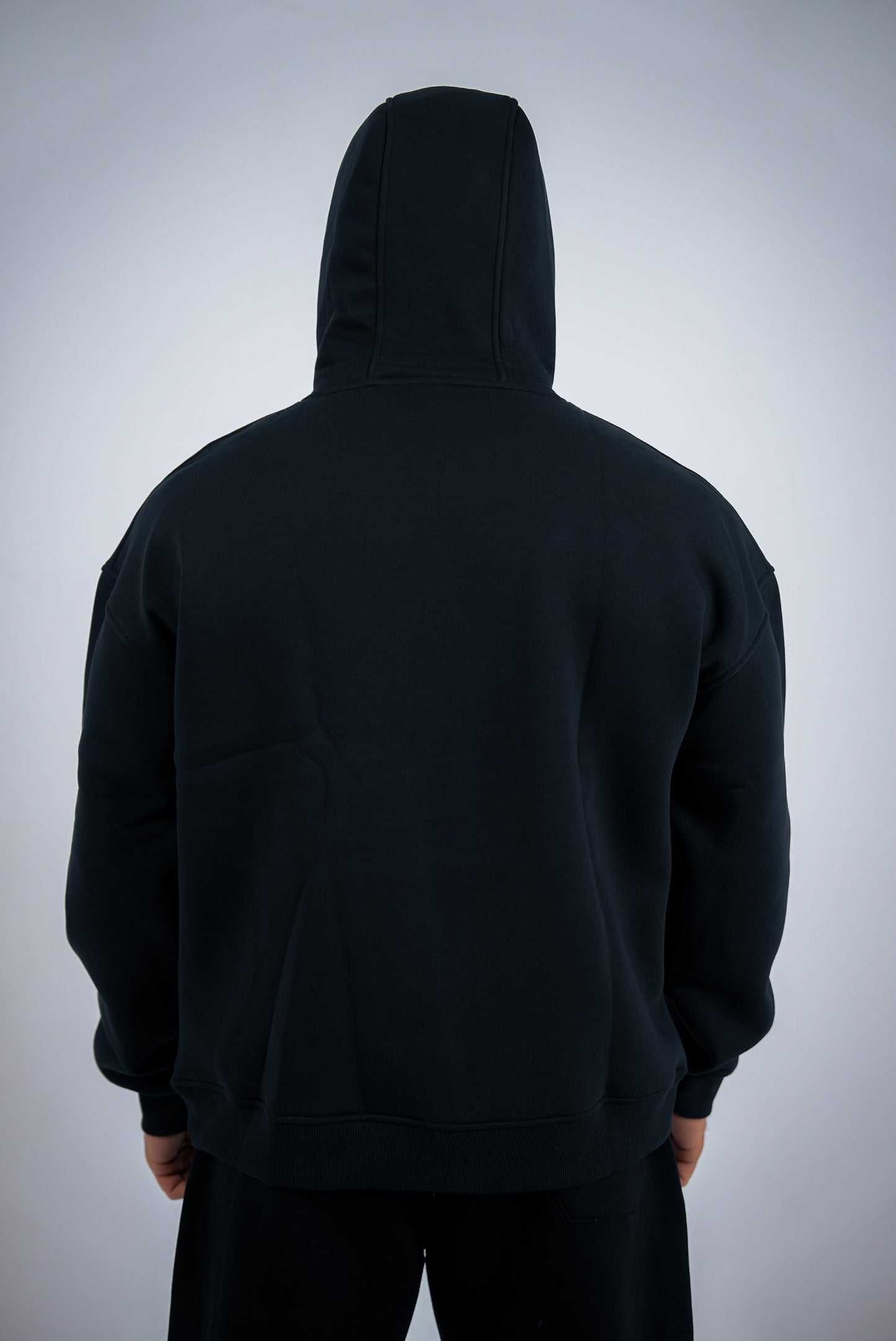 Black RAVIX hoodie worn by a person on a light gray background