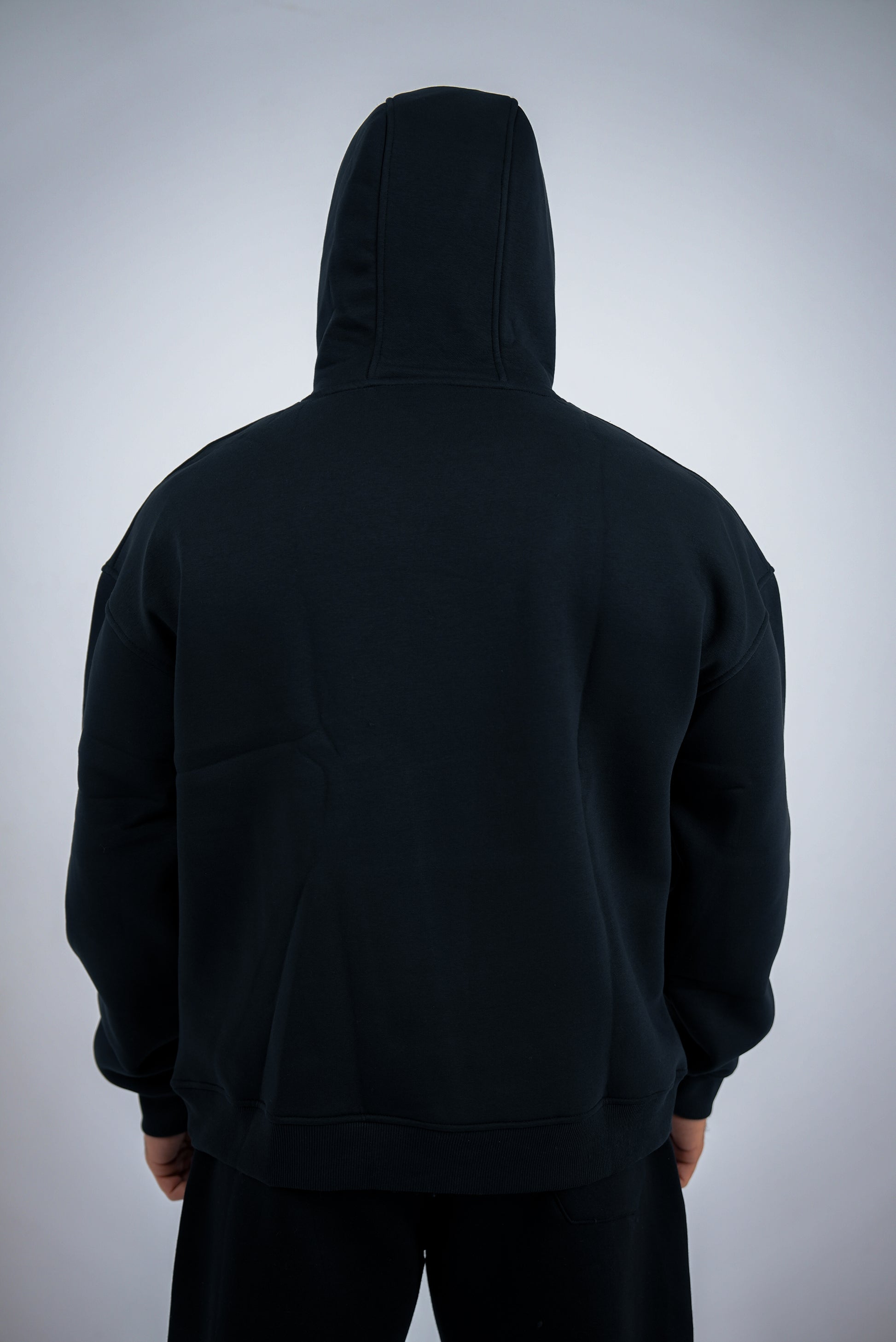 Black RAVIX hoodie worn by a person on a light gray background