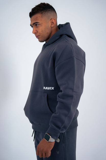 Man wearing a dark-grey hoodie with 'RAVIX' logo on a light gray background