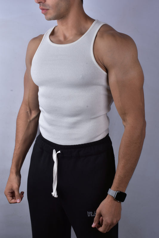 Person wearing a white tank top and black pants against a plain background