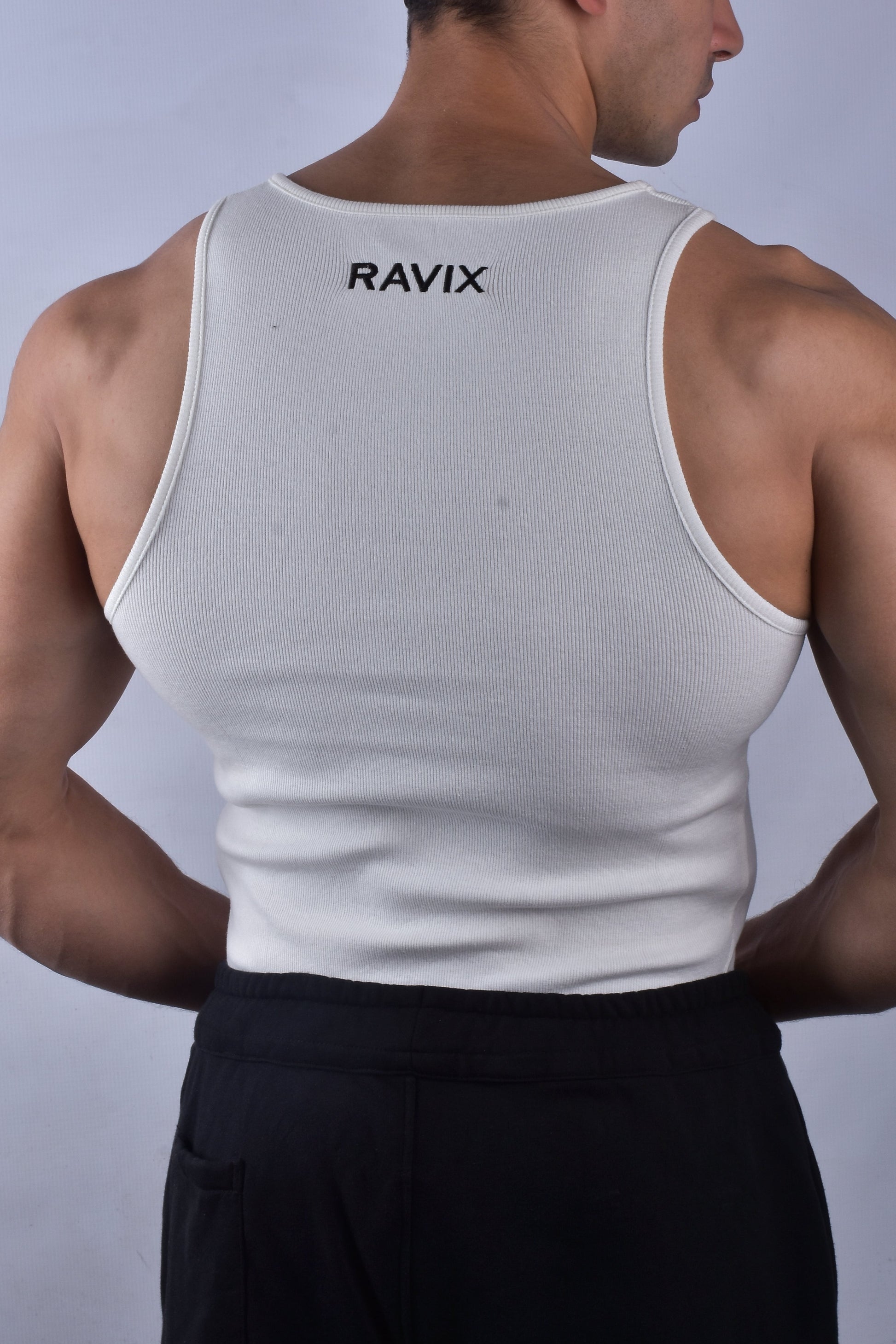Man wearing a white tank top with 'RAVIX' branding on a plain background