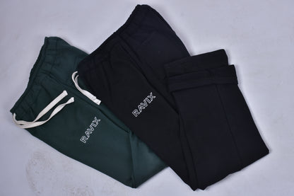 Black and green pants with 'RAVIX' branding on a light gray background