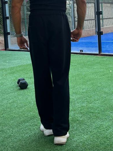 Model in black sweatpants standing on a sports court with buildings in the background